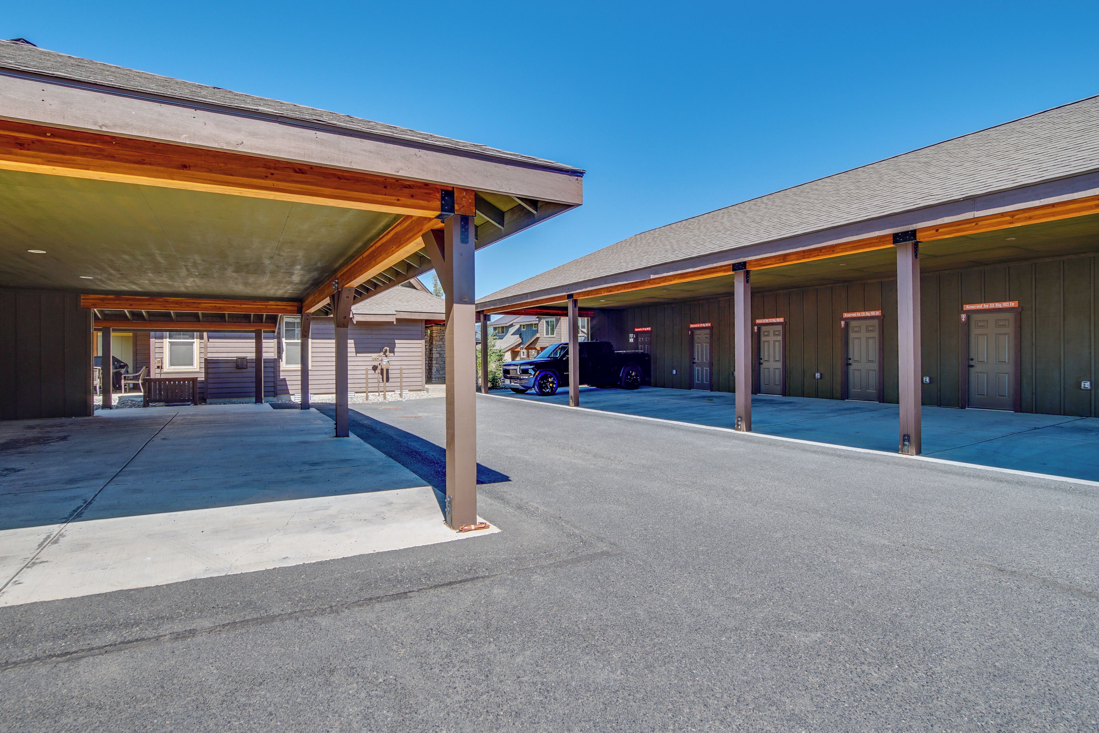 A covered parking area with multiple doors, a blue car, and a clear blue sky.