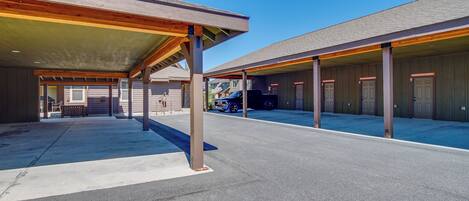 A covered parking area with multiple doors, a blue car, and a clear blue sky.