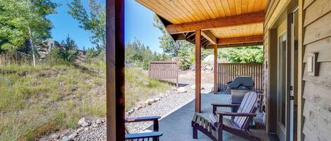 A covered outdoor patio with wooden benches and a grill.