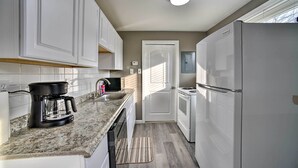 A modern kitchen with white cabinets, a built-in oven, a refrigerator, and a coffee maker on the counter. - Completely Renovated Escape ~ 1 Mile to Downtown! (Farmington Hills)