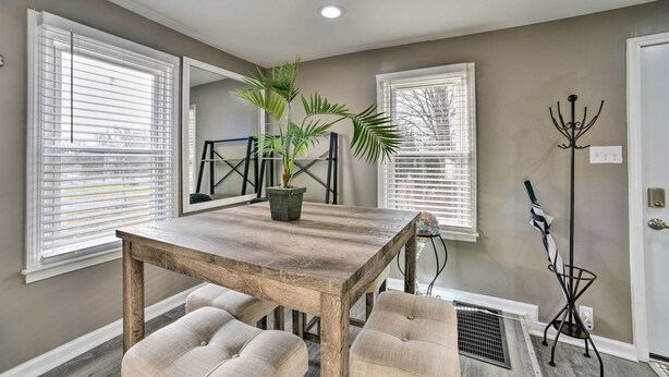 A dining area with a wooden table and cushioned chairs, a potted plant, and a coat rack. - Completely Renovated Escape ~ 1 Mile to Downtown! (Farmington Hills)
