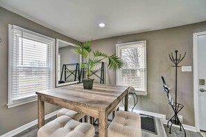 A dining area with a wooden table and cushioned chairs, a potted plant, and a coat rack. - Completely Renovated Escape ~ 1 Mile to Downtown! (Farmington Hills)
