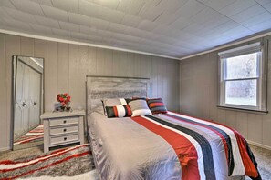 Une chambre à coucher avec un lit, une table de chevet, un miroir et une fenêtre.
