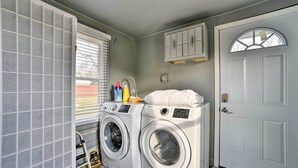 A laundry room with two front-loading washing machines, a drying rack, and a cabinet above the door. - Completely Renovated Escape ~ 1 Mile to Downtown! (Farmington Hills)