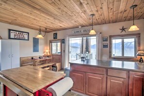 A kitchen with wooden cabinets, a wooden table, and a sign indicating 'SUMMER HOUSE'. - Serenity at Scenic Bay: Floating Cottage w/ Views! (Bayview)