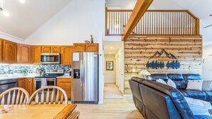 Una cocina moderna con armarios de madera, electrodomésticos de acero inoxidable y una zona de comedor con una mesa y sillas de madera.