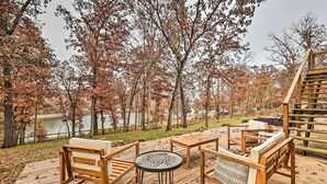 Une terrasse en bois, agréée de mobilier d’extérieur, qui offre une vue sur un lac et les arbres aux couleurs automnales.