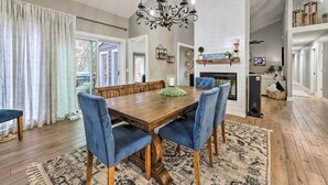 Un coin repas avec une table en bois et des chaises à revêtement bleu, un lustre et une cheminée.