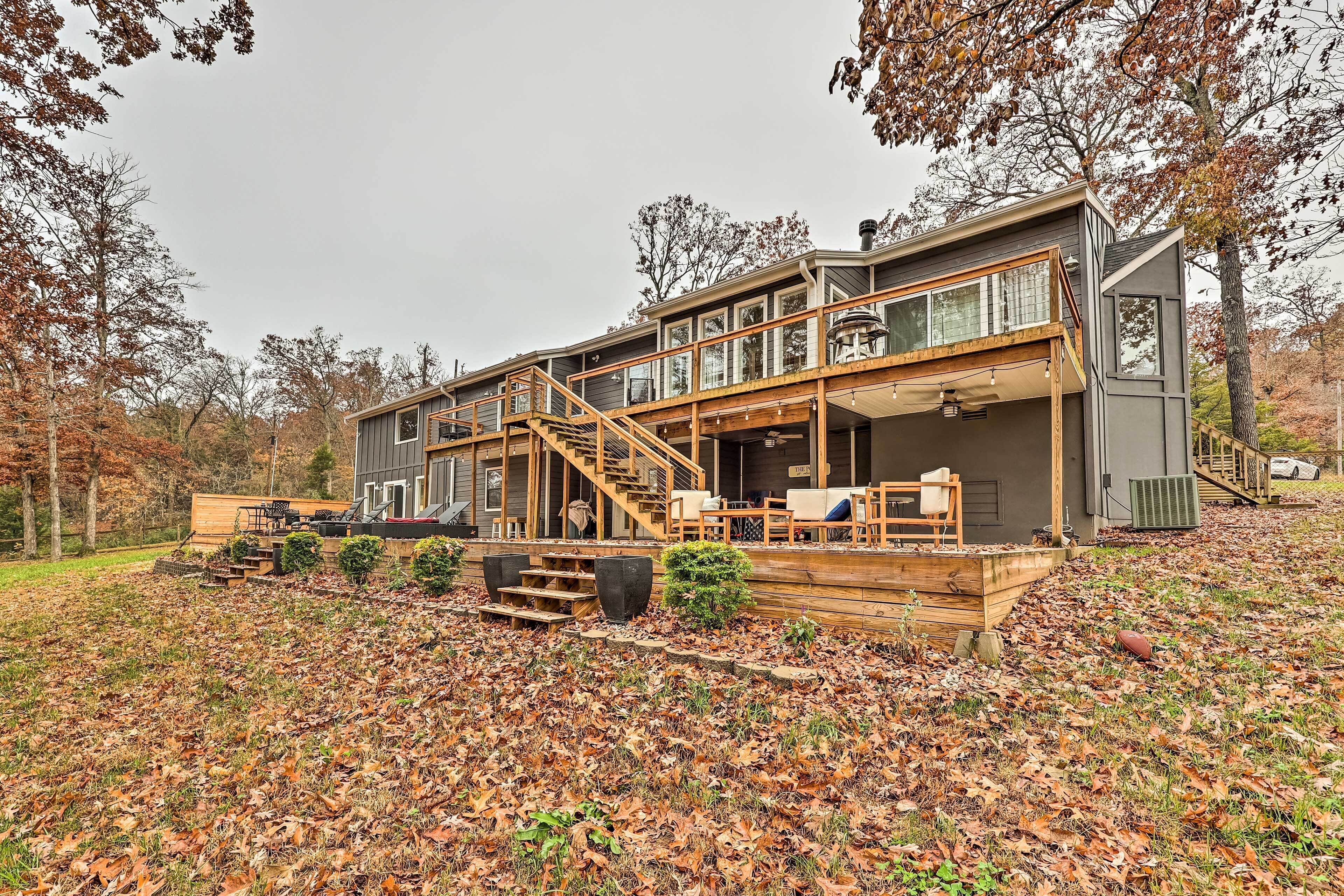 A two-story house with a wooden deck, outdoor seating, and a staircase leading to the upper level.