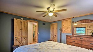 A bedroom with a bed, wooden wardrobe, and a ceiling fan. - Cozy Amish Country Cabin on Shipshewana Lake! (Shipshewana)