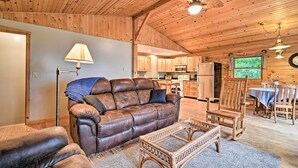 A cozy cabin interior with a leather sofa, wooden rocking chairs, a dining table, and a kitchen area. - Cozy Amish Country Cabin on Shipshewana Lake! (Shipshewana)