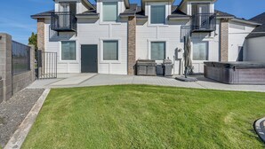 A modern two-story house with a well-maintained lawn, a barbecue area, and a covered outdoor seating space. - Pasco Condo w/ Columbia River Views + Hot Tub (Pasco)