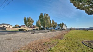 A residential street with houses, a grassy area, and a clear sky. - Pasco Condo w/ Columbia River Views + Hot Tub (Pasco)