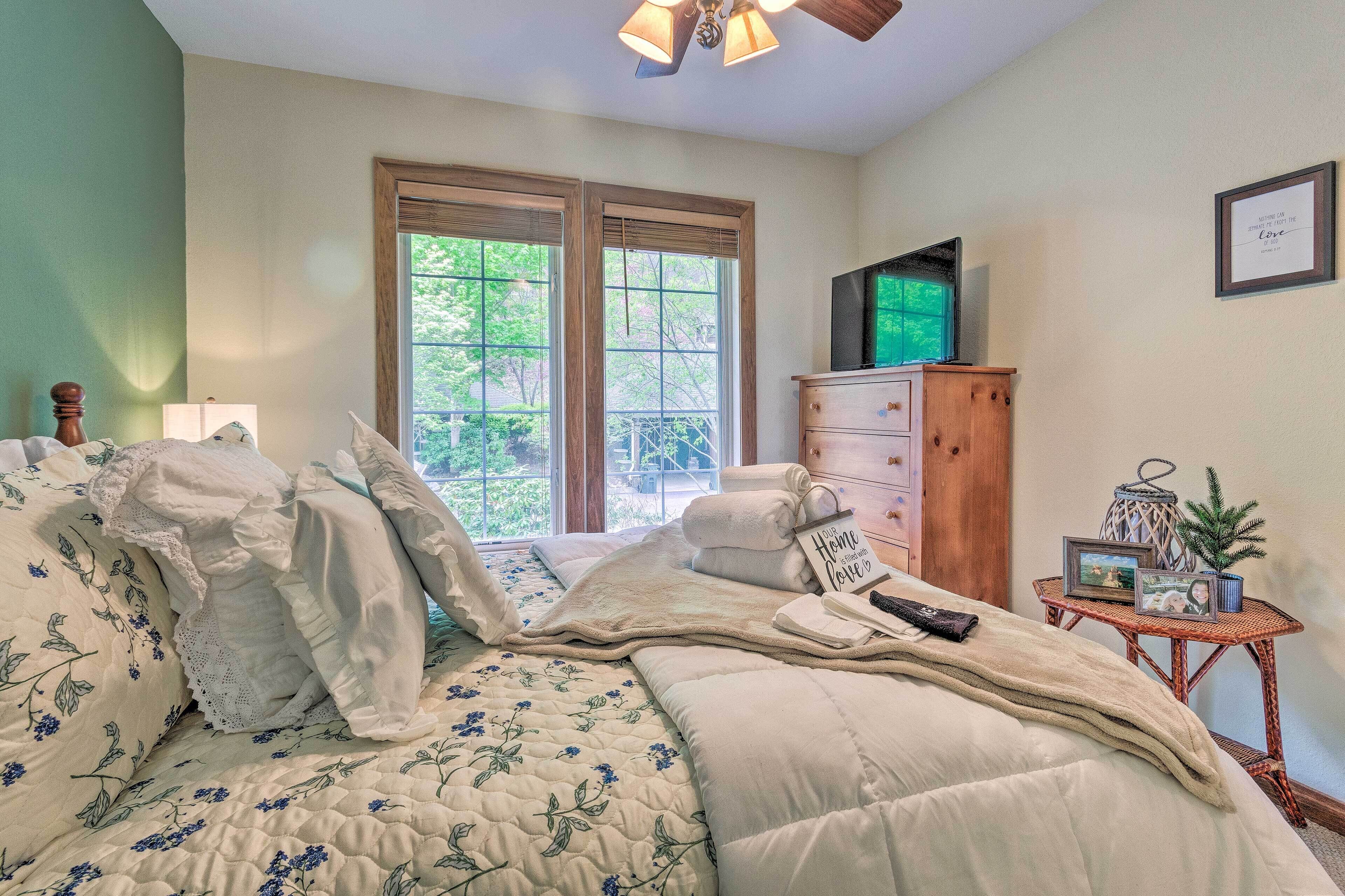 Un dormitorio con cama, cómoda, televisor y ventana con persianas.