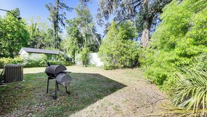 Un patio trasero con una parrilla, un porche techado y una unidad de aire acondicionado grande.
