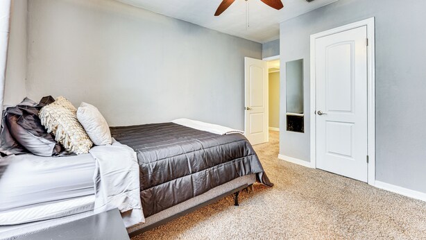 Un dormitorio con cama, ventilador de techo y una puerta.