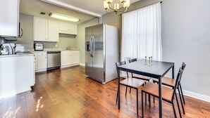Una cocina moderna con electrodomésticos de acero inoxidable, una mesa de comedor con sillas y una araña.
