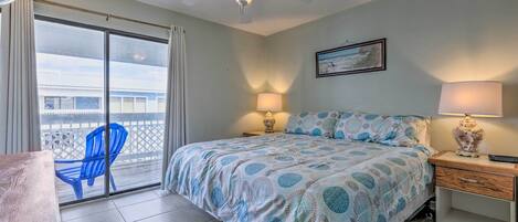 A bedroom with a bed, two bedside lamps, a ceiling fan, a desk, and a chair.