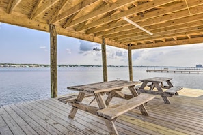 A wooden deck with picnic tables overlooking a body of water. - Gulf Shores Condo: Private Balcony & Beach Views! (Gulf Shores)