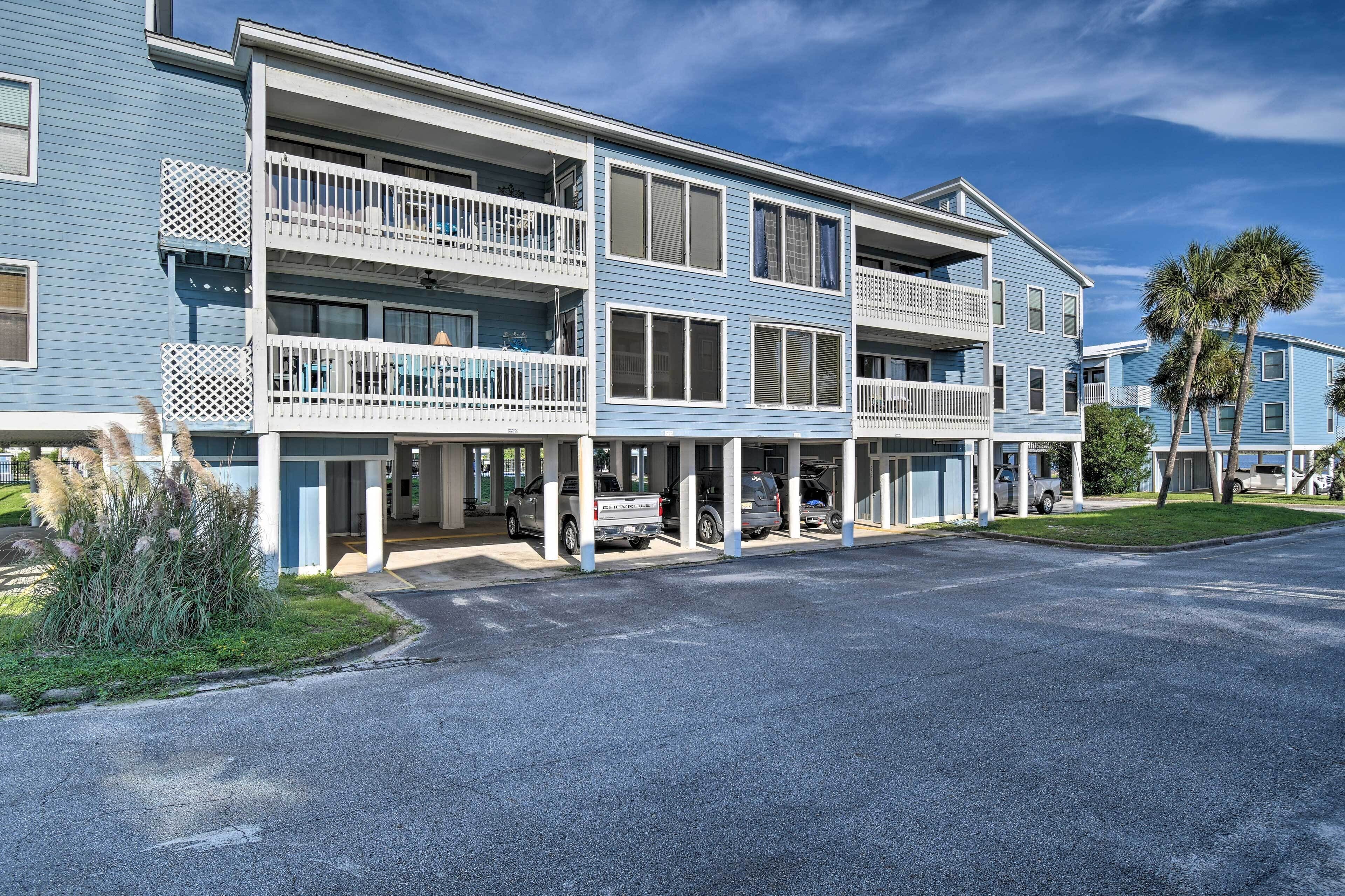 A multi-story hotel with balconies, a parking area, and a well-maintained lawn.