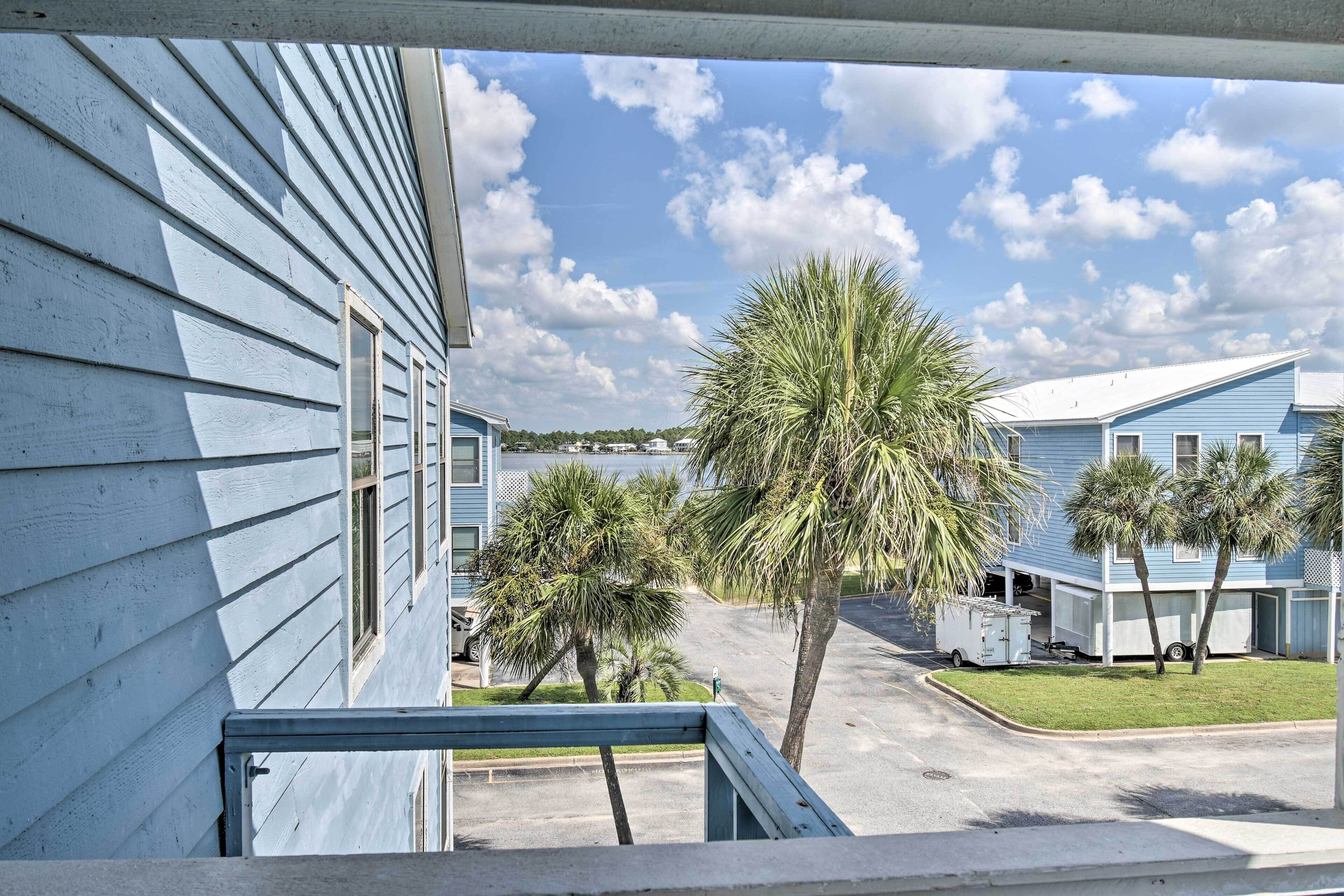 A view of a residential area with blue houses, a palm tree, and a trailer parked in the driveway.