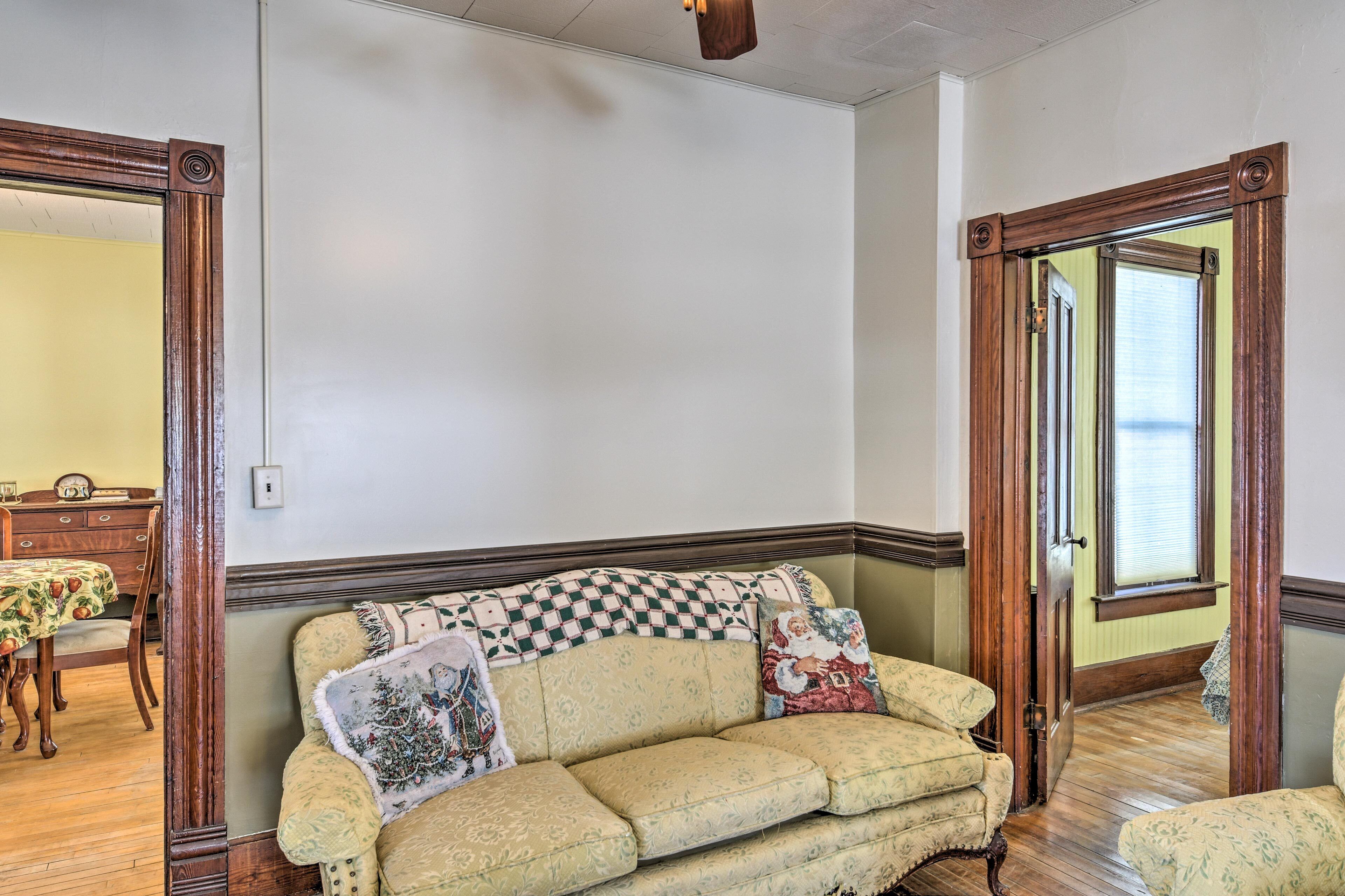 A room with a wooden-framed sofa, a dining table with chairs, and a window with blinds.