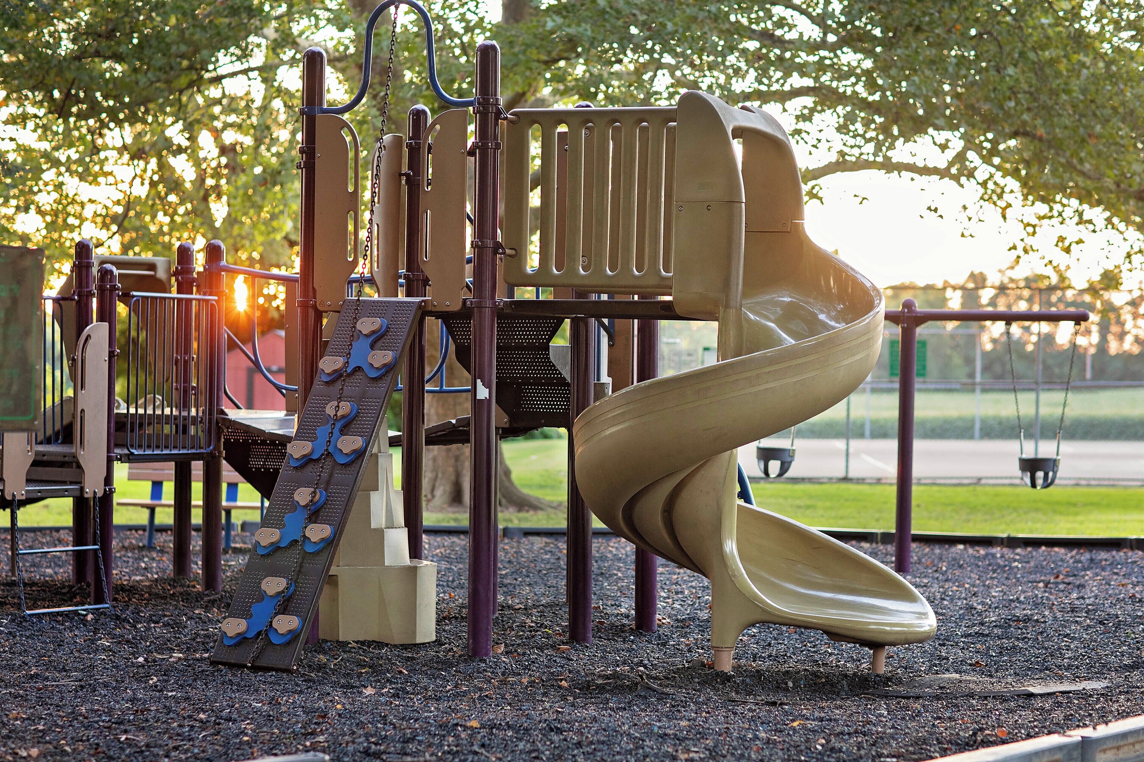A playground with a slide, climbing structures, and a swing set.
