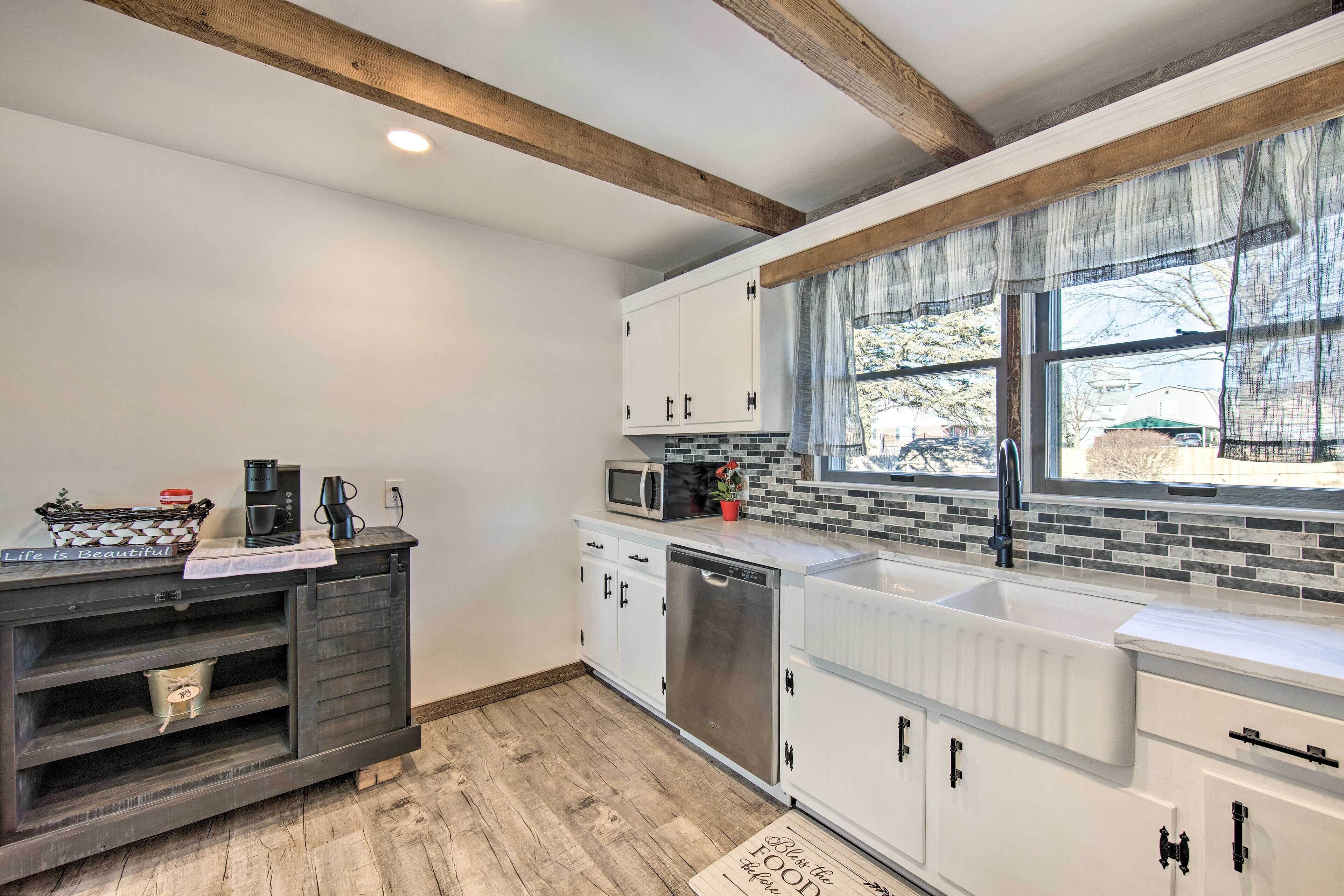 A modern kitchen with white cabinets, a stainless steel dishwasher, and a window with a view of the outside.