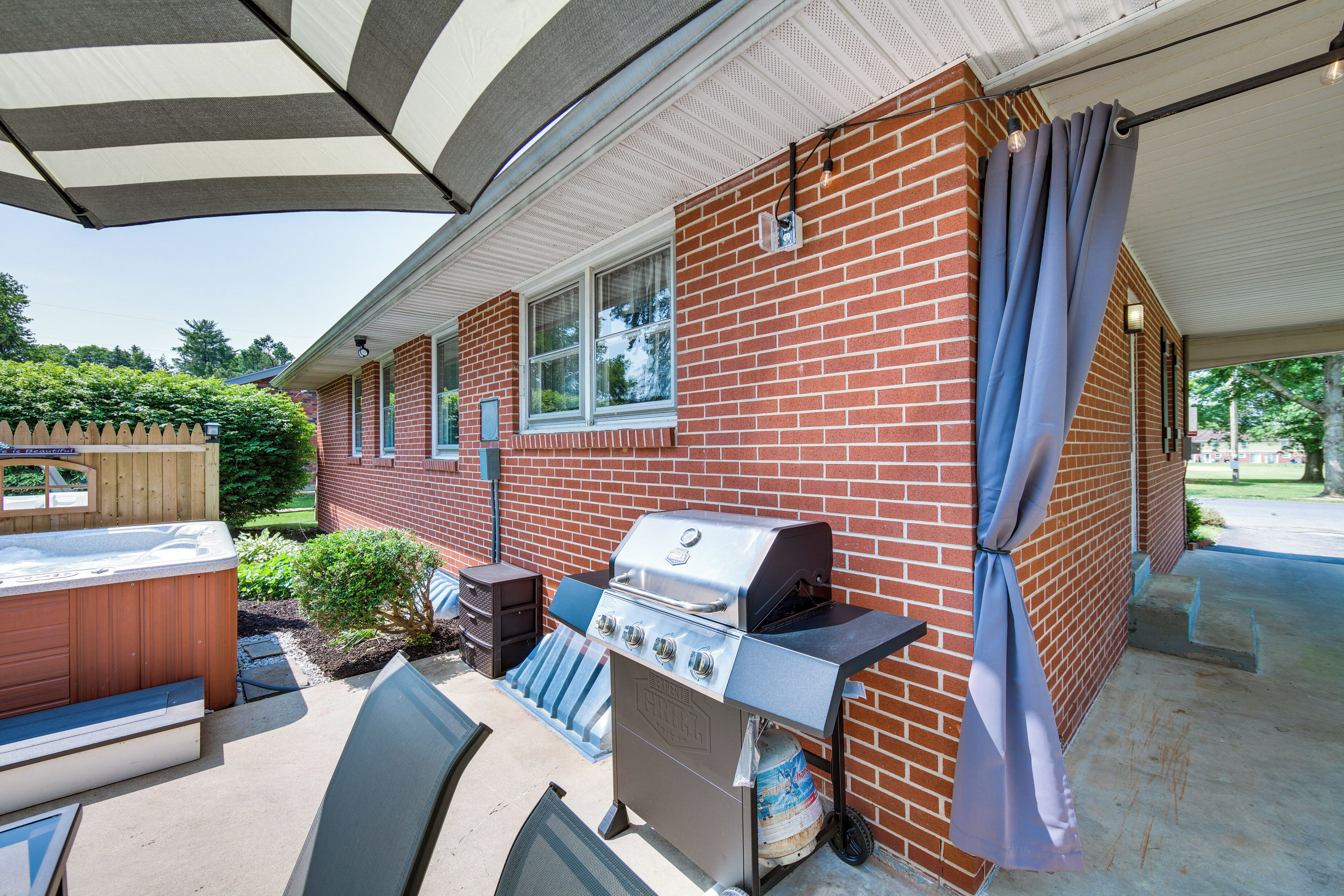 A patio with a grill, hot tub, and outdoor seating area.