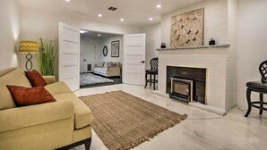 A living room with a beige sofa, a fireplace, and a large rug. - Renovated Griffith Family Home in Chicagoland Area (Griffith)