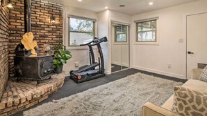 A room with a brick fireplace, a treadmill, and a fluffy rug. - Renovated Griffith Family Home in Chicagoland Area (Griffith)