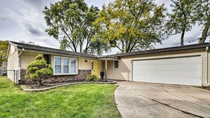 A single-story house with a garage, a small front yard with a trimmed bush, and a driveway leading to the garage. - Renovated Griffith Family Home in Chicagoland Area (Griffith)