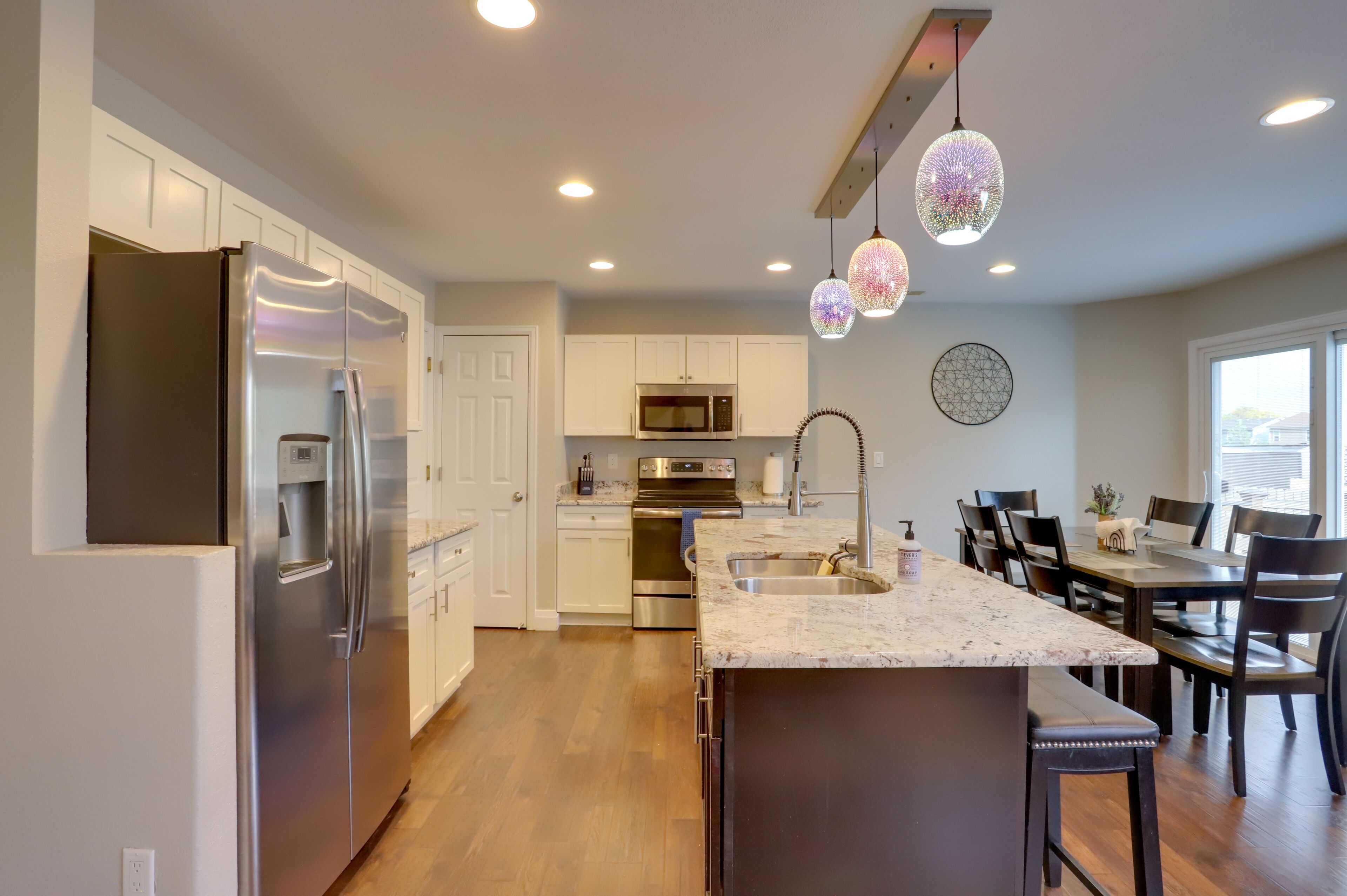 A modern kitchen with stainless steel appliances, a marble countertop, and pendant lighting.