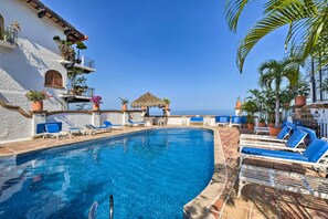 A pool area with lounge chairs, a thatched-roof structure, and potted plants. - Puerto Vallarta Condo w/ Pool - Walk to La Playa! (Puerto Vallarta)