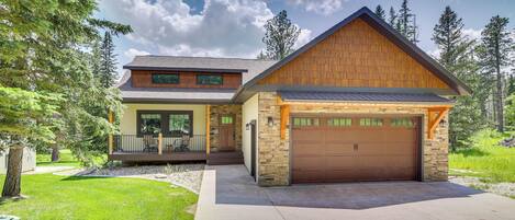 A modern two-story house with a garage, stone exterior, and a well-maintained lawn.