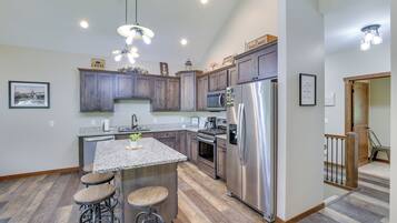 A modern kitchen with dark wood cabinets, stainless steel appliances, and a granite island with stools.