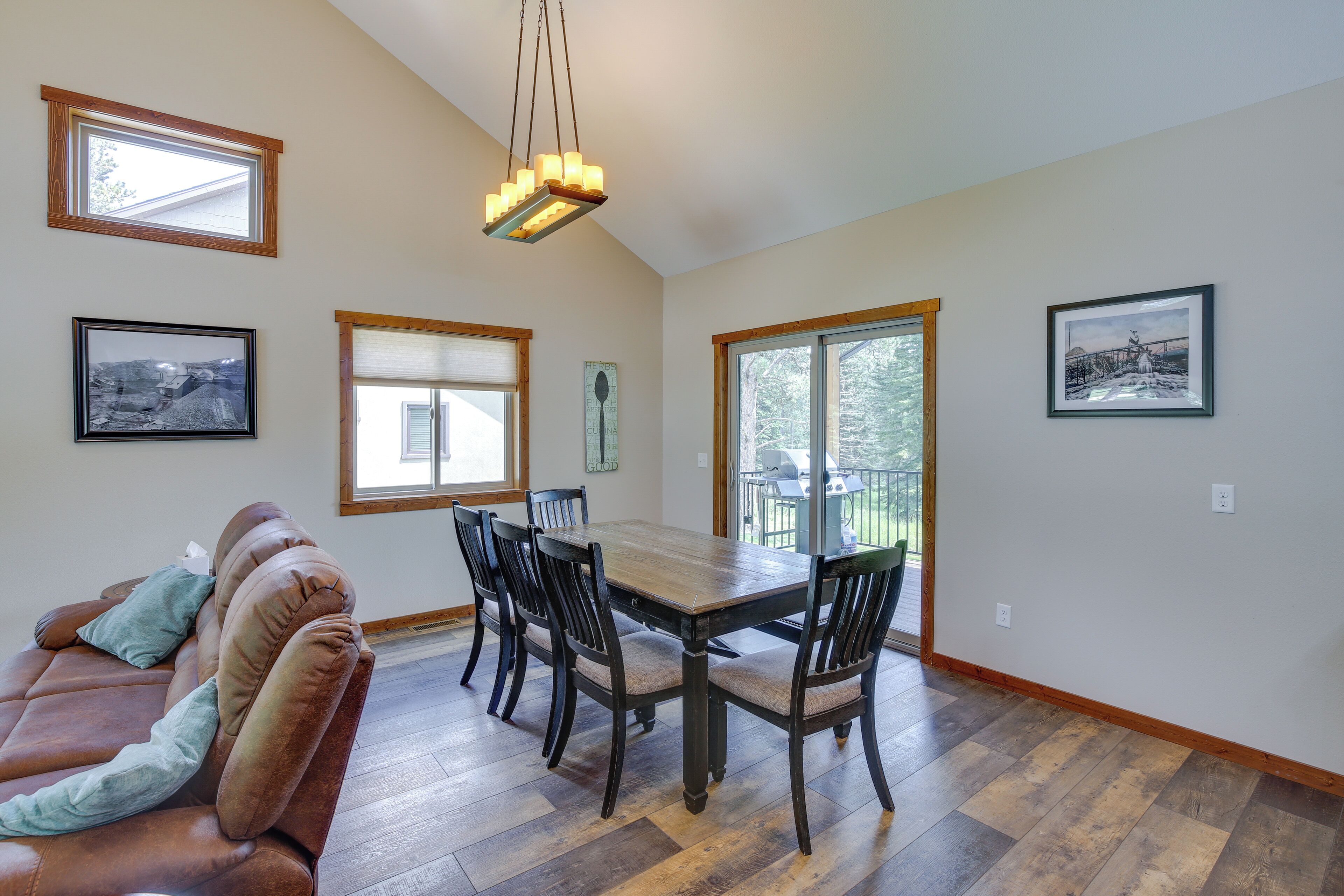 A dining area with a wooden table and chairs, a brown leather couch, and framed pictures on the walls.