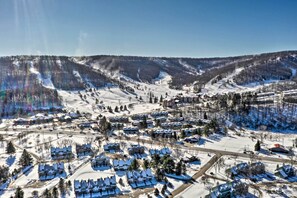 A snow-covered residential area with houses and a ski slope in the background. - Townhome w/ Fireplace - Walk to Chairlift! (Ellicottville)