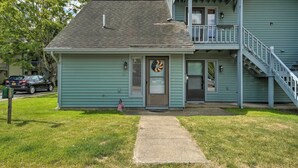 A two-story building with a front porch, a staircase to the upper level, and a small front yard. - Townhome w/ Fireplace - Walk to Chairlift! (Ellicottville)