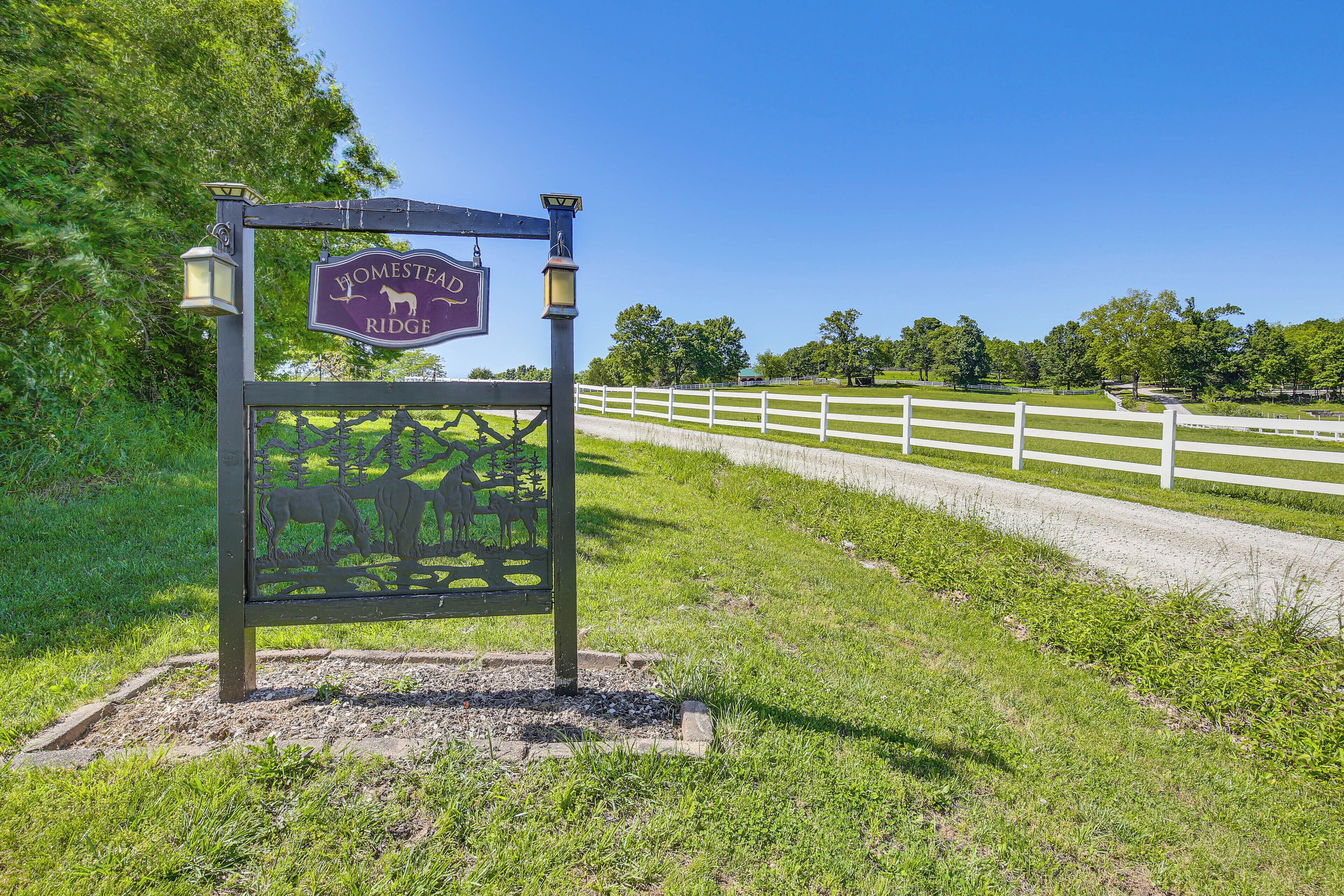 A sign for Homestead Ridge with a white fence and greenery in the background.