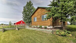 A wooden cabin with a green roof, a red barn in the background, and a well-maintained lawn. - Cabin w/ Porch & View ~ 19 Mi to West Glacier (Columbia Falls)