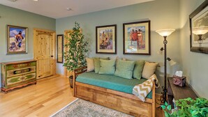 A cozy living room with a wooden sofa, a green rug, and framed pictures on the wall. - Cabin w/ Porch & View ~ 19 Mi to West Glacier (Columbia Falls)