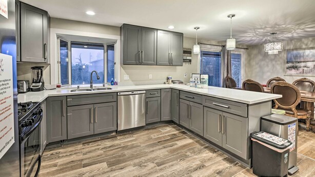 A modern kitchen with grey cabinets, stainless steel appliances, a dishwasher, and a built-in oven. - Spacious Kent Home ~ 17 Mi to Dtwn Seattle! (Kent)