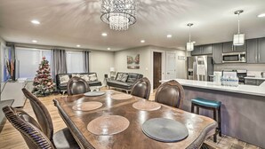 A modern kitchen with stainless steel appliances, a dining area with a wooden table and leather chairs, and a living room with a dark leather sofa and a Christmas tree. - Spacious Kent Home ~ 17 Mi to Dtwn Seattle! (Kent)