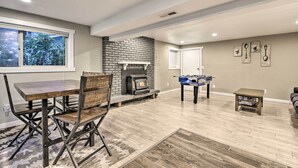 A spacious living area with a fireplace, a dining table with chairs, a foosball table, and a small table with a magazine. - Spacious Kent Home ~ 17 Mi to Dtwn Seattle! (Kent)