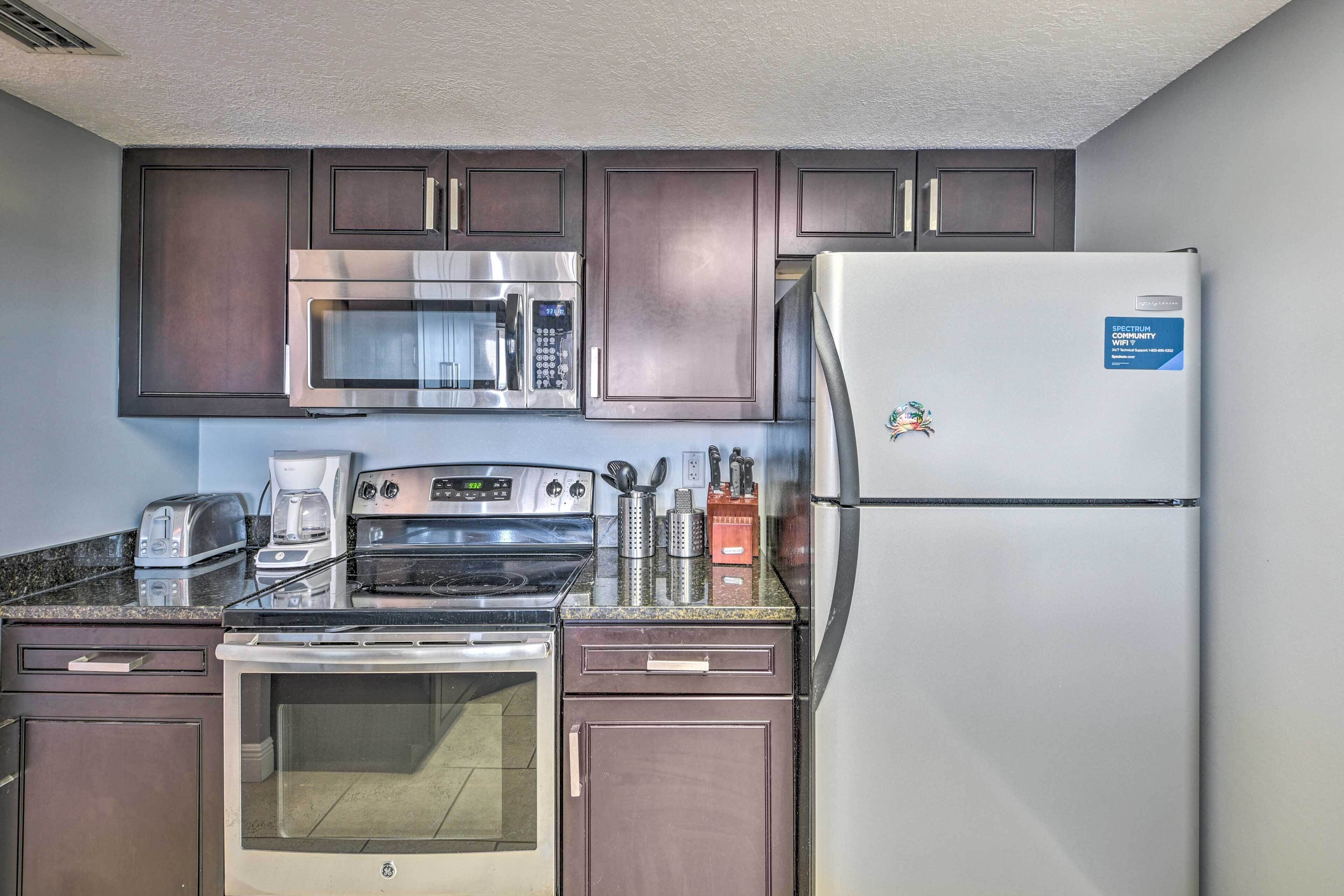 A compact kitchen with a microwave, stove, oven, and refrigerator.