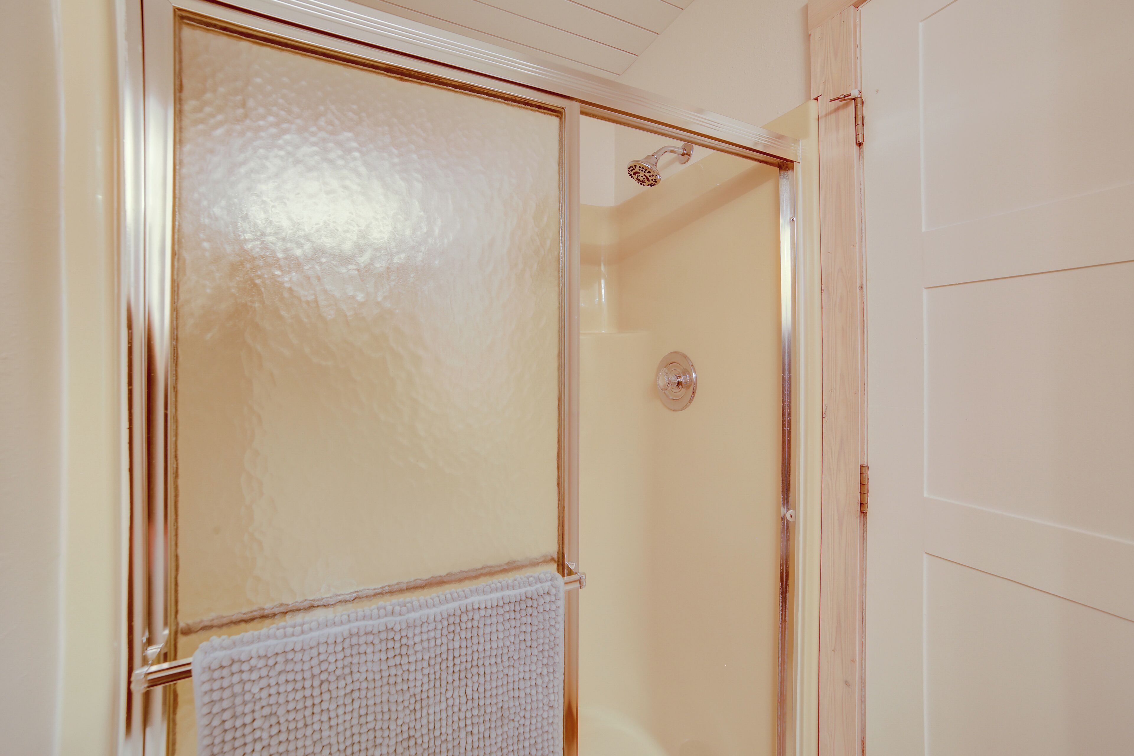 Un baño con cabina de ducha de vidrio, un perchero y una puerta.