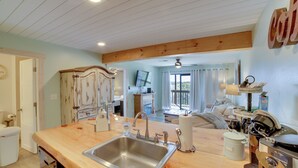 A kitchen with a sink, a coffee machine, and a dining area with a table and chairs. - Unwind Fireside: Ozark Mtn Condo w/ Resort Perks! (Branson West)