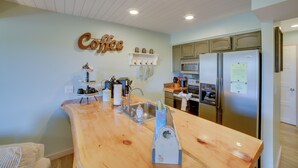 A kitchen with a wooden countertop, stainless steel appliances, and a wall-mounted coffee sign. - Unwind Fireside: Ozark Mtn Condo w/ Resort Perks! (Branson West)