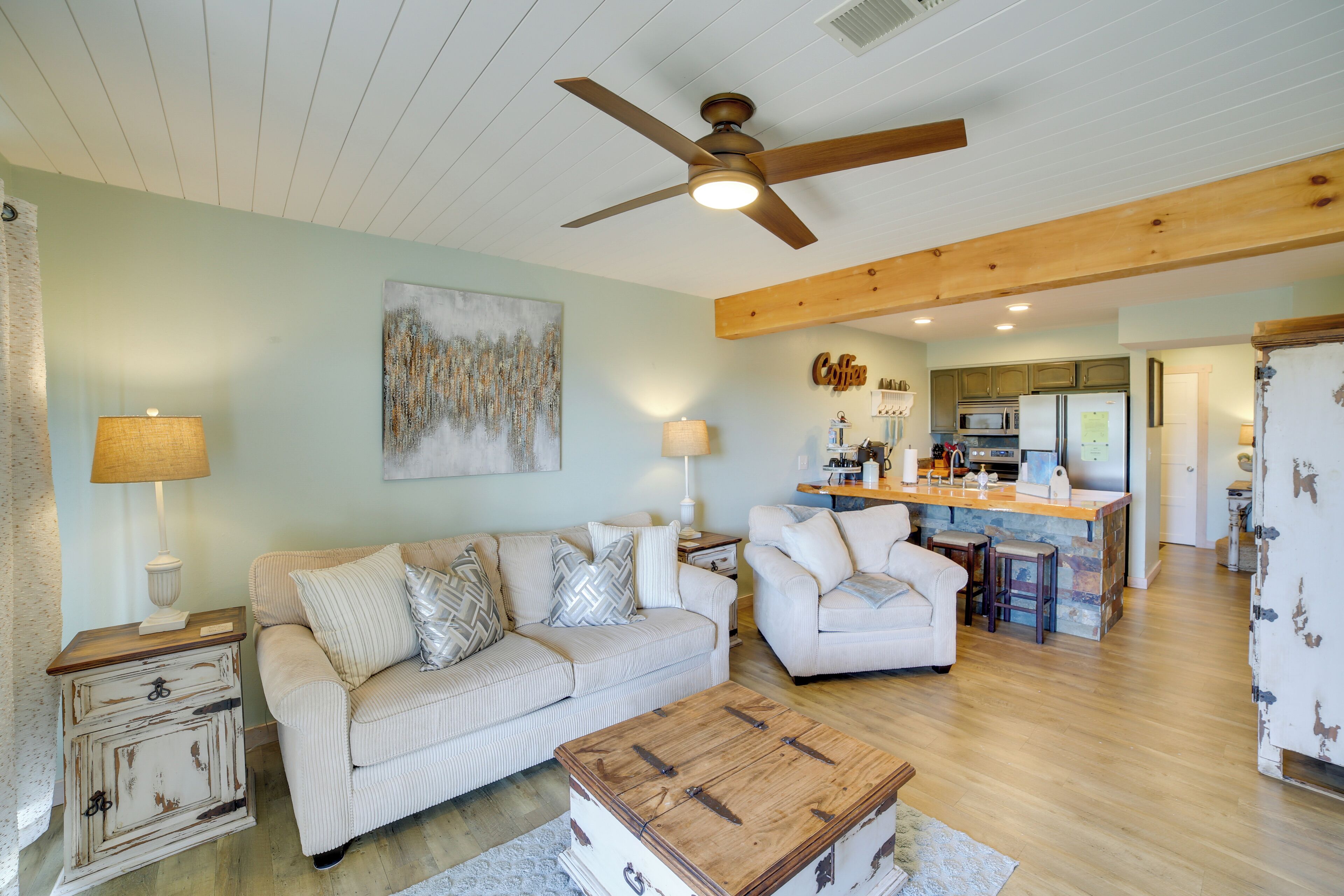 A living room with a sofa, a wooden coffee table, and a ceiling fan.